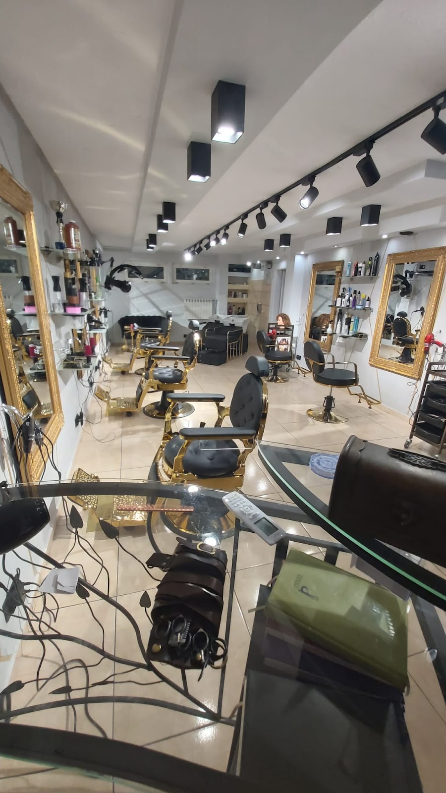 Zabytkowe czarno-złote fotele barberskie przy złotych lustrach
