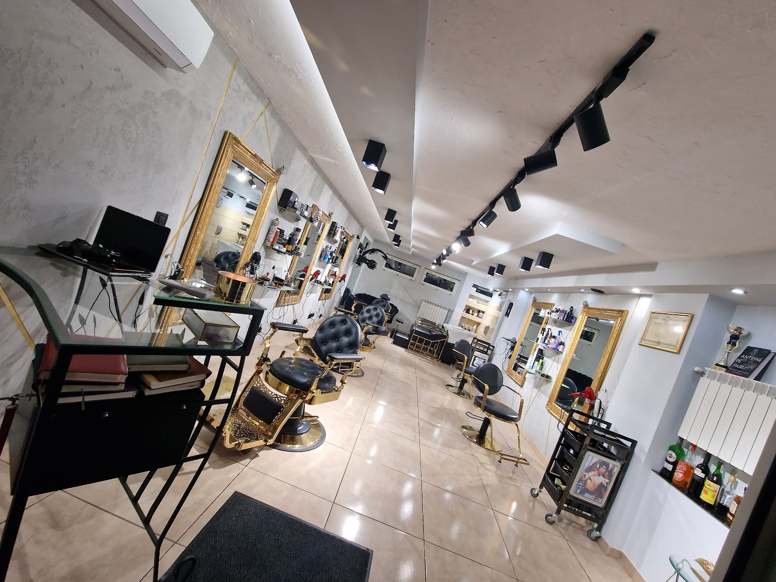 Wnętrze salonu ze złotymi lustrami i czarno-złotymi fotelami barberskimi